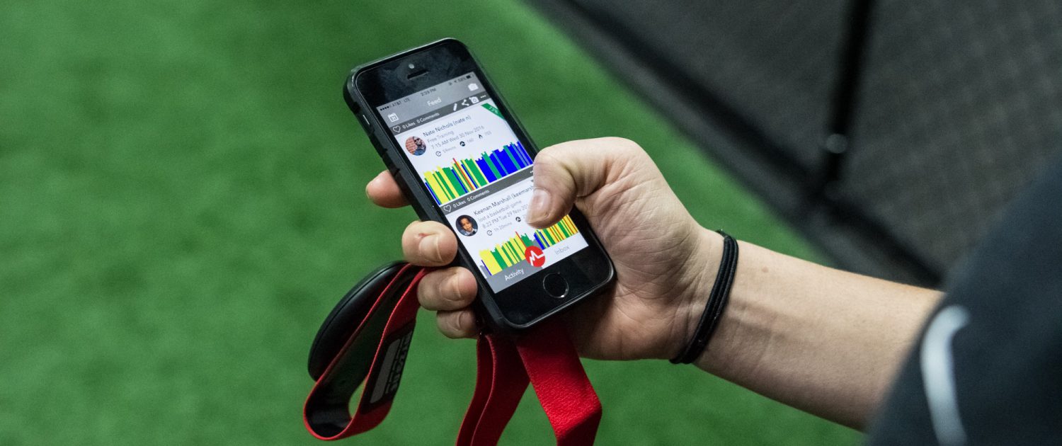 Persons hand holding myzone belt and cell phone showing the myzone app being used to track their workout.